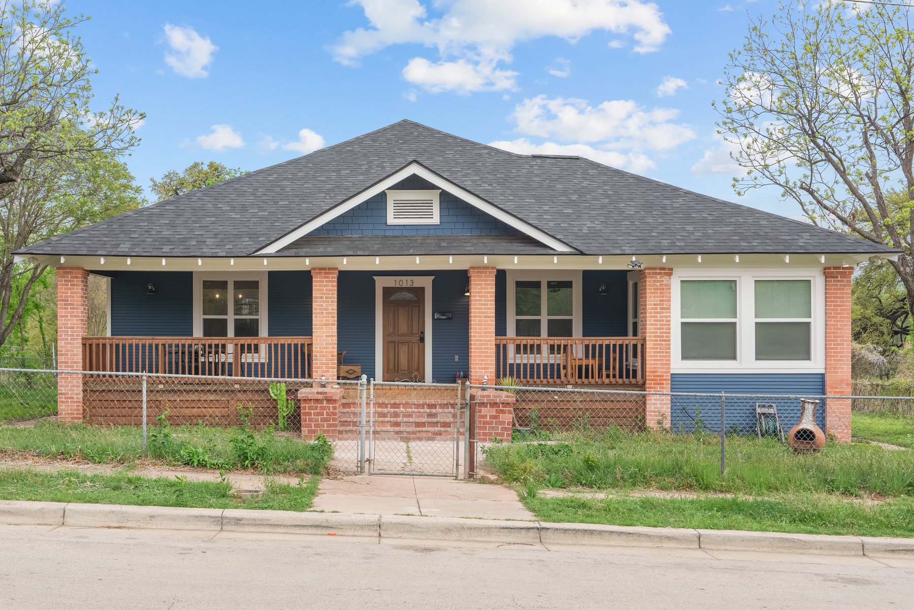 1013 Poindexter Street — a blue one-storey Craftsman bungalow with a full-width covered porch.