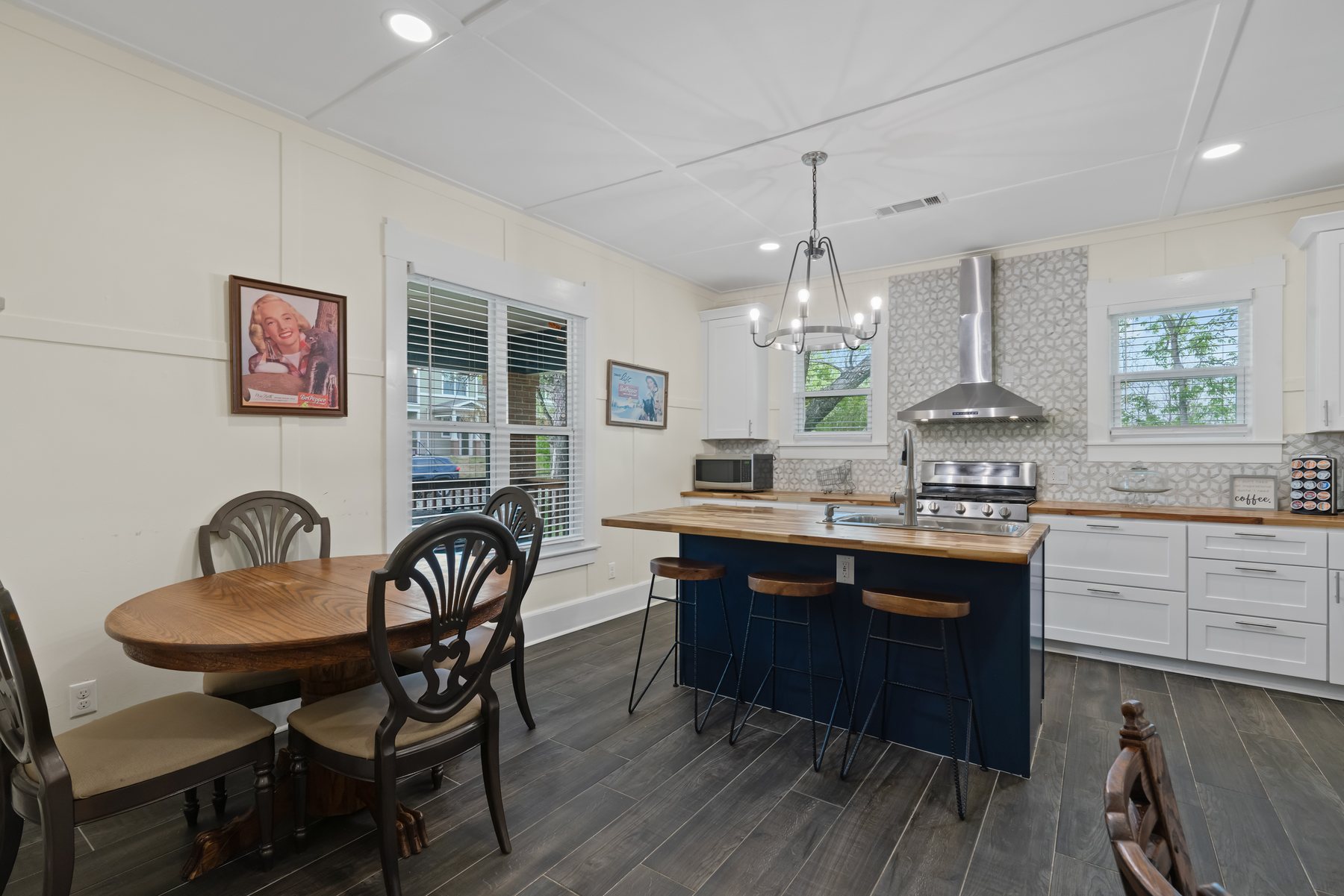 Kitchen with a blue island, butcher block counter, stainless range and hex tile backsplash.